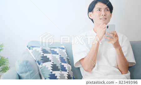 A man using a smartphone on the sofa 82349396