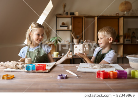 Two children making products from clay in workshop 82349969