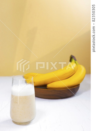 Healthy Banana smoothie on wooden board with maca and protein on orange background, Diet Food 82350305