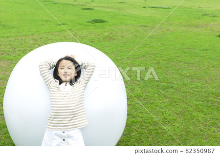 A girl leaning to the white big ball 82350987