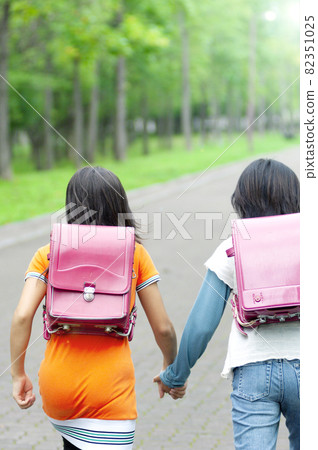 Rear view of two girls running with a backpack Rear view of two girls running with a backpack 82351025