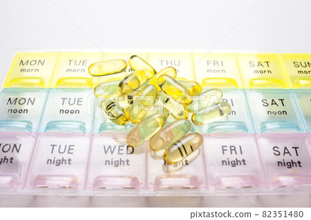Organizer for medical pills on a white isolated background close-up. Organization of taking pills of the day. Transparent vitamins lie nearby 82351480