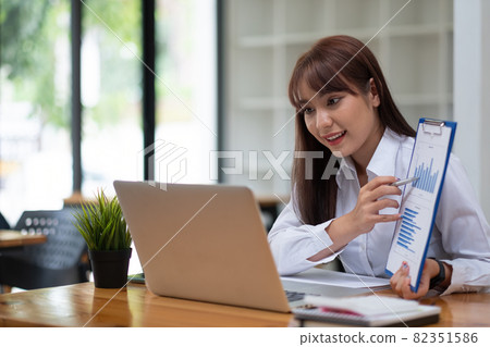 Portrait of attractive business female showing customer engagement graph report on online meeting via laptop at office Portrait of attractive business female showing customer engagement graph report on online meeting via laptop at office 82351586