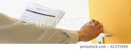 Woman knocking on door with application for employment closeup Woman knocking on door with application for employment closeup 82355990