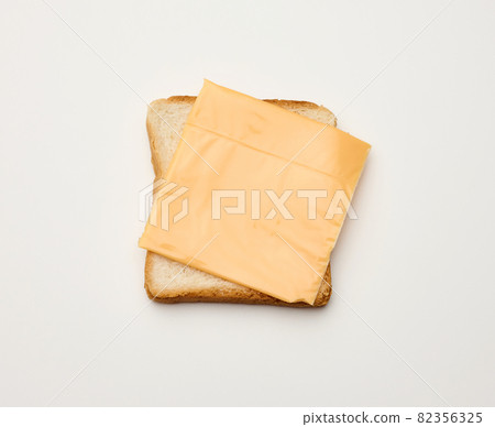 square slices of toasted bread made from white wheat flour and a slice of cheddar cheese on top. White table background square slices of toasted bread made from white wheat flour and a slice of cheddar cheese on top. White table background 82356325