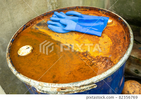 Rusty barrel at the harbour and blue gloves Rusty barrel at the harbour and blue gloves 82356769