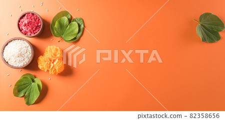 Happy Dussehra. Yellow flowers, green leaf and rice on orange background. Dussehra Indian Festival concept. Happy Dussehra. Yellow flowers, green leaf and rice on orange background. Dussehra Indian Festival concept. 82358656