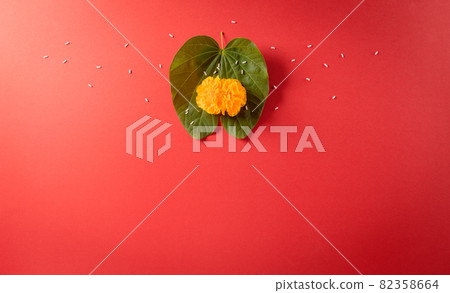 Happy Dussehra. Yellow flowers, green leaf and rice on red background. Dussehra Indian Festival concept. 82358664