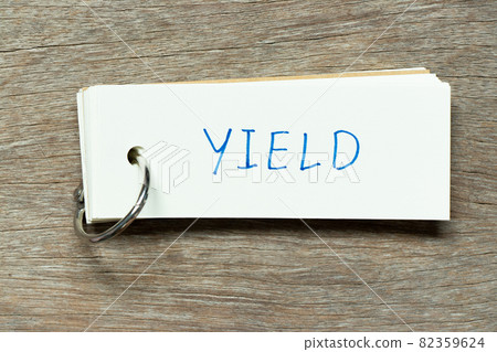 Flash card with handwriting word yield on wood background 82359624