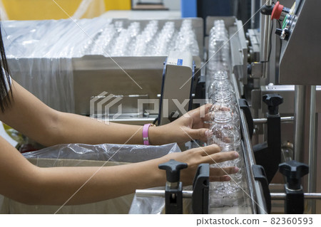 The operation put the empty PET bottles to the conveyor belt for filling process in the drinking water factory. 82360593