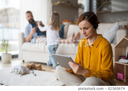 Businesswoman with tablet working indoors at home, everyday life and home office with child concept. Businesswoman with tablet working indoors at home, everyday life and home office with child concept. 82360674