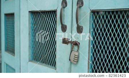 Vintage wooden folding door with metal rusted latch and unlocked padlock 82361423