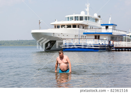 A young oligarch swims in the sea against the background of his own yacht A young oligarch swims in the sea against the background of his own yacht 82361516