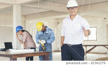 Asian engineer man brainstorming construction building contractor civil worker parners team meeting at constrcution site. Blueprint engineer hardhat worker helmet on table. Engineer teamwork consult 82362279