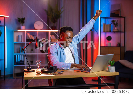 Man looking at computer screen and gesturing emotionally 82363082