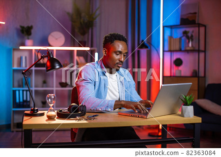 African man sitting home office and typing on laptop 82363084