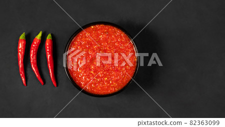 Adjika on a black background. Hot chili peppers harissa sauce. Homemade rose harissa in a bowl. Copy space, top view Adjika on a black background. Hot chili peppers harissa sauce. Homemade rose harissa in a bowl. Copy space, top view 82363099