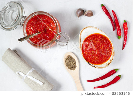 Harissa sauce or adjika on a white background. Hot chili pepper sauce. Traditional Tunisia, Georgian and Arabic cuisine. View from above. Harissa sauce or adjika on a white background. Hot chili pepper sauce. Traditional Tunisia, Georgian and Arabic cuisine. View from above. 82363146