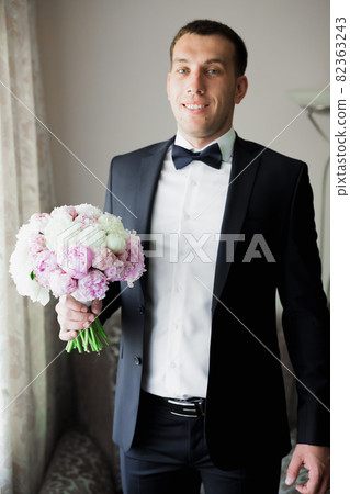 Grooms morning preparation. Handsome man getting dressed and preparing for the wedding Grooms morning preparation. Handsome man getting dressed and preparing for the wedding 82363243