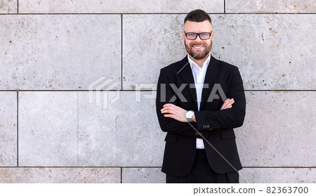 Portrait of confident successful businessman in formal suit with crossed hands smiling at camera 82363700