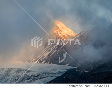 Soft focus. Minimalist mountain landscape with fiery snow peak. Wonderful minimalist landscape with big snowy mountain peaks above low clouds. Soft focus. Minimalist mountain landscape with fiery snow peak. Wonderful minimalist landscape with big snowy mountain peaks above low clouds. 82364111