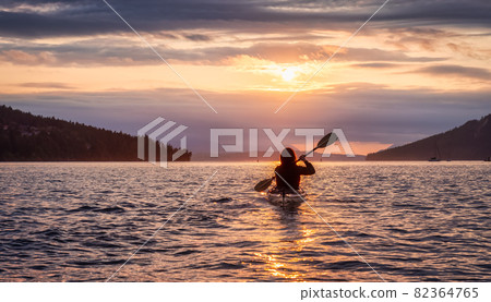 Adventurous Woman on Sea Kayak paddling in the Pacific Ocean. Adventurous Woman on Sea Kayak paddling in the Pacific Ocean. 82364765