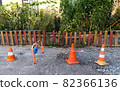 Three different traffic cones are blocking path to someone's garden with fence at private property. Cone with white and red stripes is used as warning sign on construction site and places of danger 82366136