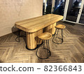 Restaurant or cafeteria in modern loft style. Large massive dinner table and chairs with steel legs are standing on old vintage floor next to decorative brick wall against reinforced plastic doors 82366843
