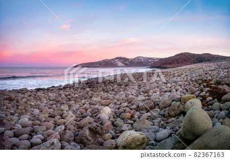 The surface of the beach on the north ocean is covered with large polished round stones of gray color of different sizes 82367163
