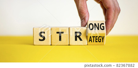 Strong strategy symbol. Businessman turns a wooden cube with words 'strong strategy'. Beautiful yellow table, white background, copy space. Business and strong strategy concept. 82367882