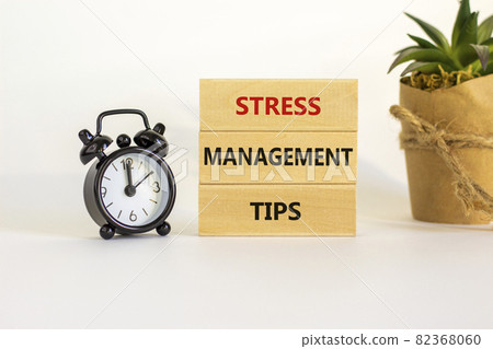 Stress management tips symbol. Wooden blocks with words 'Stress management tips'. Beautiful white background. Black alarm clock. Psychological, business and stress management tips concept. Copy space. 82368060