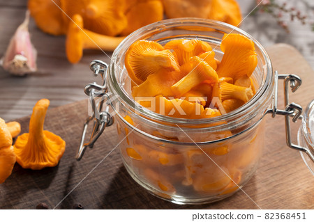 Preserving chanterelle mushrooms in a jar with spices and herbs. Pickling wild edible mushrooms Preserving chanterelle mushrooms in a jar with spices and herbs. Pickling wild edible mushrooms 82368451
