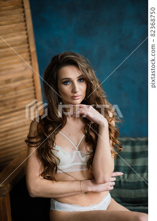 Beautiful woman in lingerie showing long legs sexy pose standing at bed over her bedroom near big window. Bride boudoir. Wedding morning. 82368750