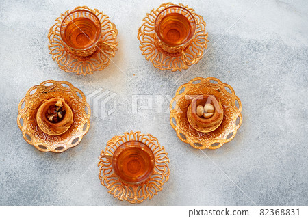 Turkish baklava and Turkish tea in oriental dishes on gray background Turkish baklava and Turkish tea in oriental dishes on gray background 82368831