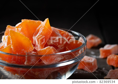 Natural farm homemade candied pumpkin fruits sprinkled with powdered sugar in a glass bowl on a wooden table 82369534