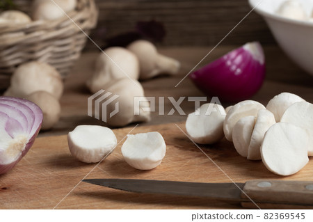 Cooking edible puffball mushrooms. Cutting peeled mushrooms on a cutting board, closeup 82369545