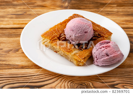 Turkish dessert kunefe served with ice cream on wooden background Turkish dessert kunefe served with ice cream on wooden background 82369701