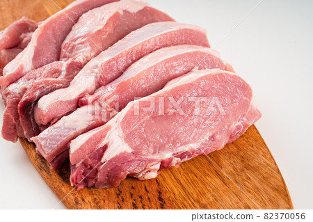chopped into pieces raw pork on a wooden cutting board on a white background. chopped into pieces raw pork on a wooden cutting board on a white background. 82370056