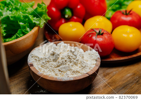 a wooden bowl of flour and vegetables on the kitchen table. farm products 82370069