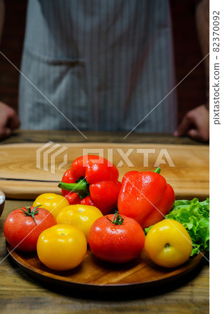 yellow and red tomatoes, lettuce and bell pepper with water drops. man in apron. 82370092