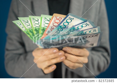 Qazaqstan money tenge in hands against the background of a woman in gray jacket Qazaqstan money tenge in hands against the background of a woman in gray jacket 82372885