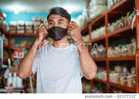 small business owner wearing face mask in front of his shop small business owner wearing face mask in front of his shop 82377137