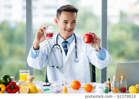 Male nutritionist with fruit and pills in medical office 82379818