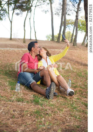 Mature woman taking selfie kissing with husband Mature woman taking selfie kissing with husband 82379928