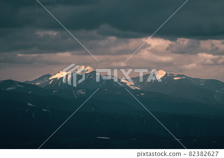 Wonderful dramatic landscape with big snowy mountain peaks above low clouds. Atmospheric large snow mountain tops in cloudy sky. Wonderful dramatic landscape with big snowy mountain peaks above low clouds. Atmospheric large snow mountain tops in cloudy sky. 82382627