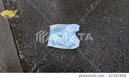 Used blue medical mask lies on the wet asphalt. Covid 19. Pandemic. Dirty medical mask. Pollution of nature. Used blue medical mask lies on the wet asphalt. Covid 19. Pandemic. Dirty medical mask. Pollution of nature. 82382808