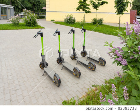Four city scooters on the asphalt. Four parked scooters in the summer city. Modern youth mode of transport. Four city scooters on the asphalt. Four parked scooters in the summer city. Modern youth mode of transport. 82383738