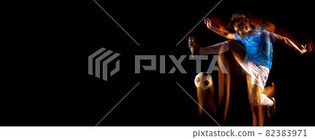 Full-length portrait of young sportsman, soccer football player training isolated over black background in mixed light. Flyer Full-length portrait of young sportsman, soccer football player training isolated over black background in mixed light. Flyer 82383971