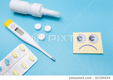 Catch a cold. Flu season. Disease. Pills, nasal spray, thermometer, and antibiotics. Seasonal cold concept. Health care. Sad smiley with google eyes. Round eyes. Catch a cold. Flu season. Disease. Pills, nasal spray, thermometer, and antibiotics. Seasonal cold concept. Health care. Sad smiley with google eyes. Round eyes. 82384044