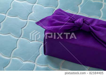 A gift wrapped in a purple furoshiki A gift wrapped in a purple furoshiki 82384405
